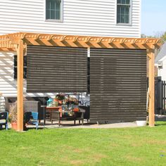 an outdoor patio with a wooden pergolan attached to the side of a house