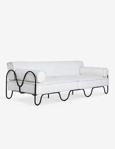 a white couch sitting on top of a white floor next to a black metal frame