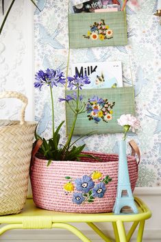 two baskets with flowers are sitting on a table next to a wallpapered wall