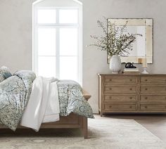 a bedroom with a bed, dresser and mirror on the wall in front of it