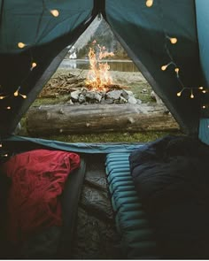 the inside of a tent is lit up with fairy lights and there is a fire in it