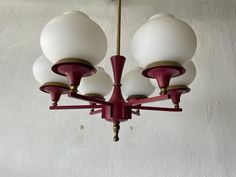 a chandelier hanging from the ceiling with five white and red shades on it