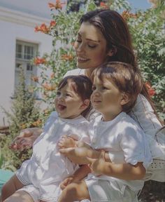 a woman holding two small children in her arms