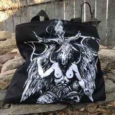 "Baphomet Large Tote Bag THIS ITEM IS MADE TO ORDER Classic tote shape with oversized dimensions of 20\" wide, 15\" tall and 4\" deep Poly Canvas fabric Navy blue inner liner with 1 zipper pocket and 1 double pocket for organization 1.5\" wide cotton webbing strap in black Artwork by: Nat Jones" Black Alternative Style Bags, Gothic Black Bags With Large Capacity, Black Gothic Bag With Large Capacity, Gothic Large Capacity Black Bag, Gothic Large Capacity Shoulder Bag, Black Gothic Shoulder Bag, Gothic Black Shoulder Bag For Cosplay, Alternative Style Black Bags For Festivals, Gothic Black Bag For Alternative Fashion