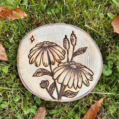 a piece of wood that has flowers on it in the grass with leaves around it