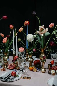 a table topped with lots of different types of vases filled with flowers and candles