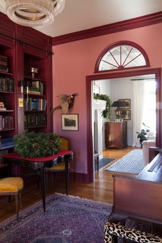 a living room filled with furniture and bookshelves next to a doorway that leads to a hallway