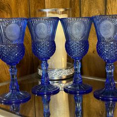 three blue glass goblets sitting on top of a table next to a candle