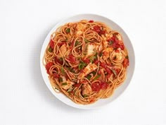 a white bowl filled with pasta and sauce on top of a table next to a fork