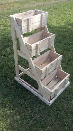 three wooden crates stacked on top of each other in the grass, with one being used as a planter