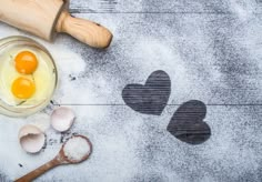 two eggs are in a glass bowl next to some spoons and an egg slice