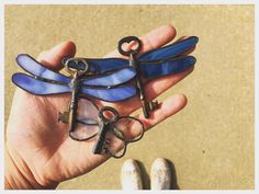 a person holding three dragonfly shaped keys in their hand