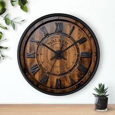 a wooden clock with roman numerals is on the wall next to a potted plant