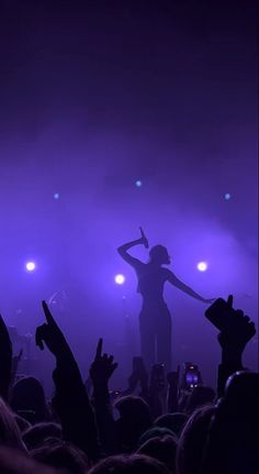 a woman standing on top of a stage with her arms in the air