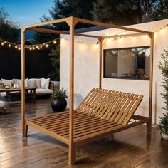 a bed sitting on top of a wooden floor next to a white wall with string lights