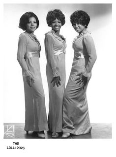 three women in long dresses standing next to each other with their hands on their hips