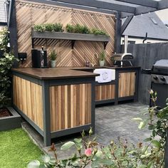 an outdoor kitchen with wooden cabinets and potted plants