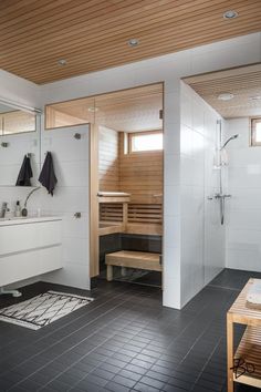 a bathroom with black tile flooring and white walls, along with a wooden ceiling