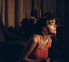 a woman with green eyes sitting on the floor in front of a couch and looking off into the distance