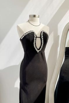 a mannequin wearing a black dress with pearls on it