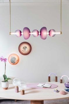 three lights hanging from the ceiling above a table with various objects on it and a potted plant