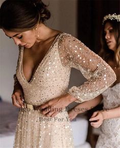 two women standing next to each other wearing dresses with sequins on the back