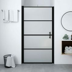 a bathroom with white walls and black trim on the glass door, toiletries and towel racks