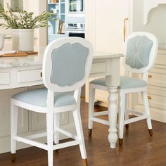 two white chairs with blue upholstered back rest at a kitchen table