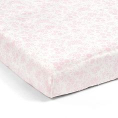 a pink and white floral print sheet on top of a baby crib bedding