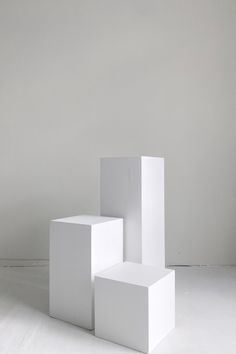 three white cubes sitting on top of each other in the middle of a room