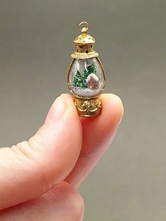 a miniature christmas ornament in the shape of a snow globe with trees inside