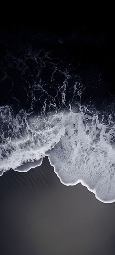 an aerial view of the ocean with waves coming in from the shore and dark sky