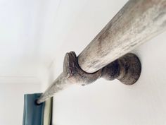 an old wooden pipe is hanging on the wall next to a window sill in a white room