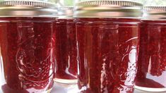 four jars filled with red liquid sitting on top of a table