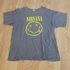 This Vintage T-Shirt Features The Iconic Nirvana Smiley Face Design From 1992. It Is A Must-Have Item For Any Nirvana Fan Or Collector. The Shirt Is A Size Large For Men Or A Medium For Women, With A Regular Fit And A Classic Gray Color. The Shirt Is Made By Anvil And Is Pre-Owned. This Item Is Perfect For Anyone Looking To Add A Unique And Nostalgic Piece To Their Clothing Collection. A10 Nirvana Smiley Face, Smiley Face Design, Classic Gray, Must Have Items, Face Design, Rock Band, Smiley Face, Nirvana, Vintage Tshirts