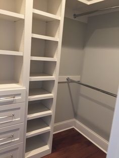 a walk in closet with white shelves and drawers