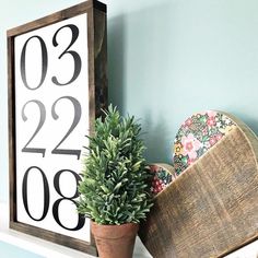 a wooden clock sitting on top of a shelf next to a potted plant