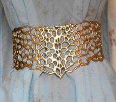 a close up of a gold metal belt on a blue dress with holes in it