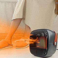 an electric heater sitting on the floor next to a woman's feet