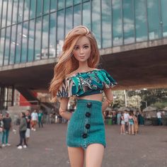 a barbie doll wearing a green skirt and crop top in front of a tall building