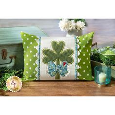 a green and white pillow sitting on top of a wooden table next to a potted plant