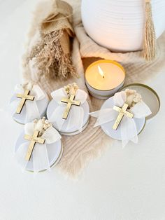 three candles with bows on them next to a white vase and other items that include a cross