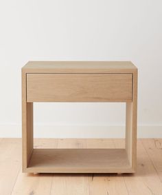 a wooden table sitting on top of a hard wood floor next to a white wall