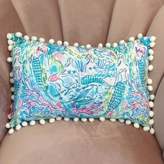 a blue and pink pillow with pom - poms on the back of it