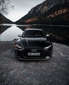 a black sports car parked on the side of a mountain road next to a body of water