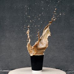 a cup filled with liquid sitting on top of a white table next to a wall