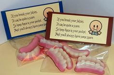 some fake teeth are in plastic bags on a table next to a sign that says if you treat your babies, i can't tell the same