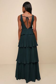 the back of a woman wearing a dark green dress with tiered ruffles