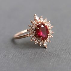 a close up of a ring with a red stone in the center and white diamonds around it