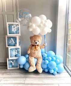 a teddy bear sitting on top of blue balloons